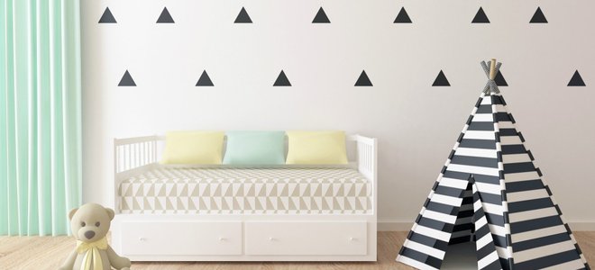 A kid's room with triangles stenciled on the wall.