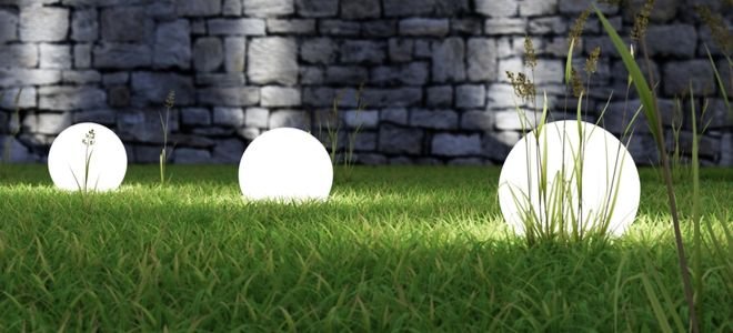 bright globe landscape lights on lawn near stone wall