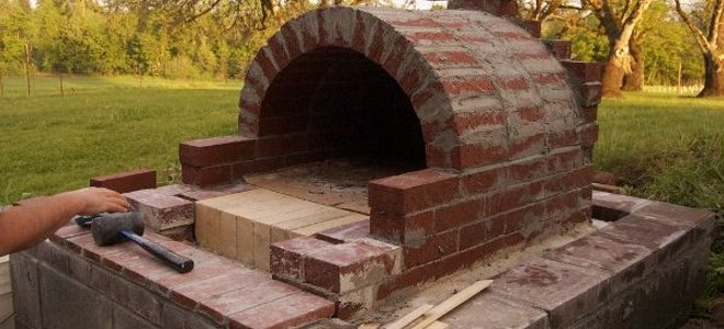 The construction of an outdoor brick pizza oven.