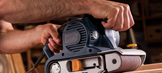 smoothing wood plank with electric sander
