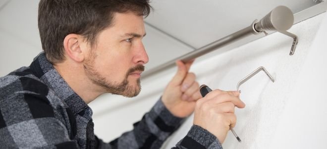 man installing a bracket support for a curtain rod