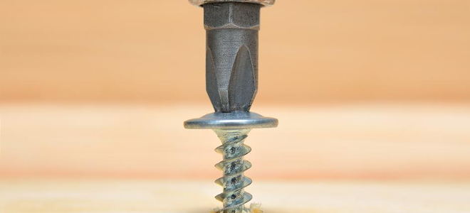 A screwdriver driving a screw into a piece of wood. 