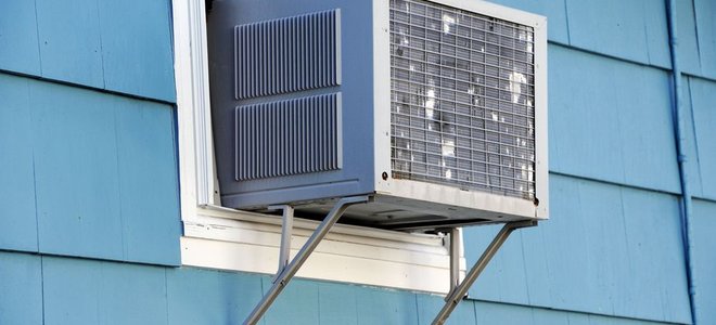 A window air conditioning unit in a blue house.
