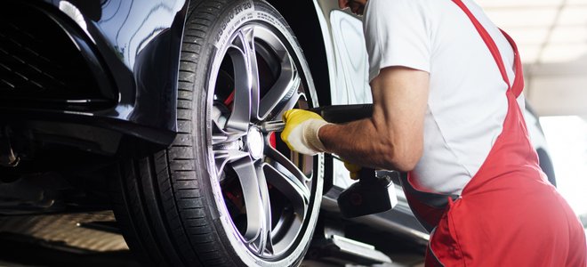 A man changes a tire on a car.