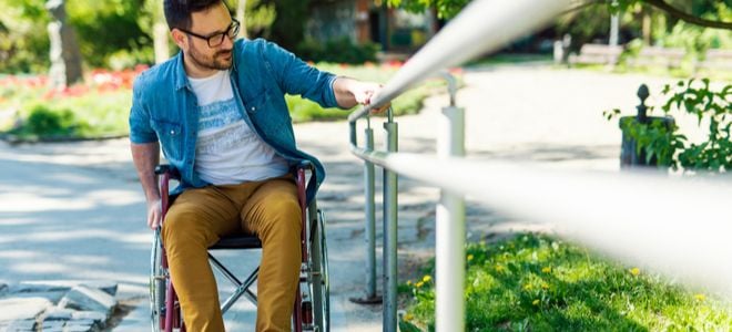 man on wheelchair holding railing outside