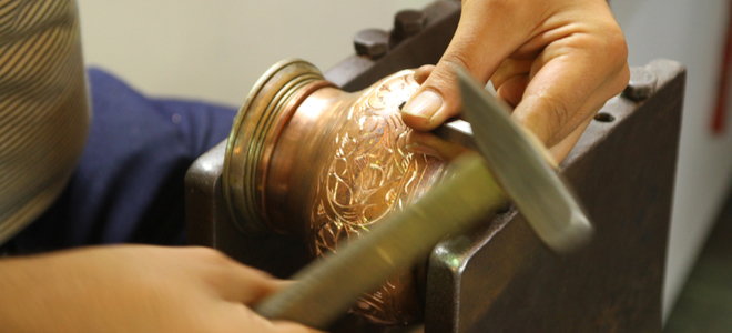 hands crafting an elaborate copper cup