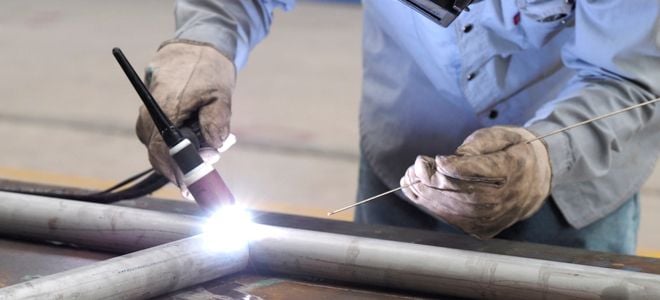 gloved hands using welder to connect pipes