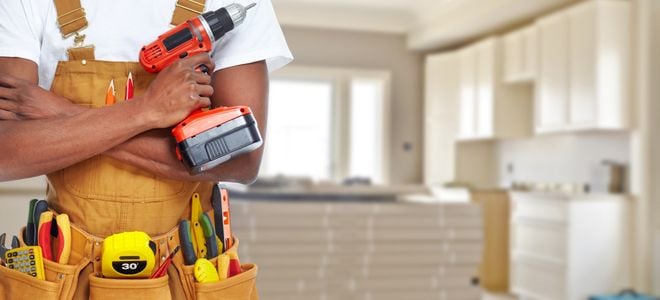 worker with tools in front of kitchen being remodeled