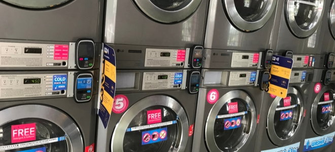 row of washing machines in a store with deal stickers
