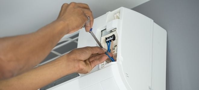 hands installing a wall mounted AC unit