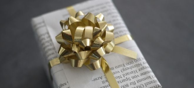 a present wrapped in newspaper with gold ribbon and bow