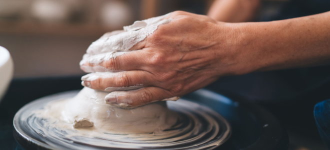hands shaping clay on pottery wheel