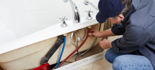 plumber checking pipes in bathtub