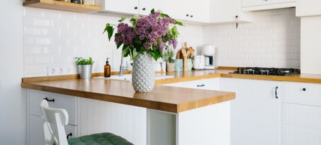 white kitchen island connected to wall with flowers and chair