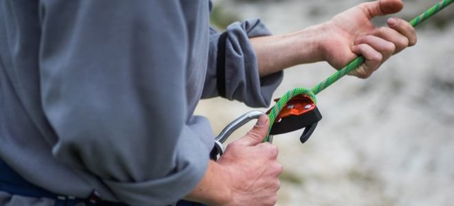 hands feeding climbing rope through a carabiner
