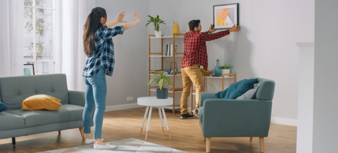 two people hanging a picture in a clean, well designed room