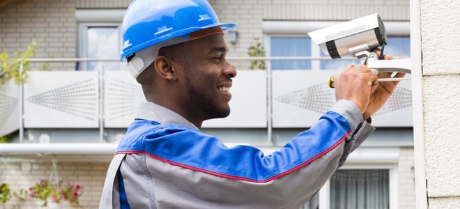 smiling man installing security camera outdoors
