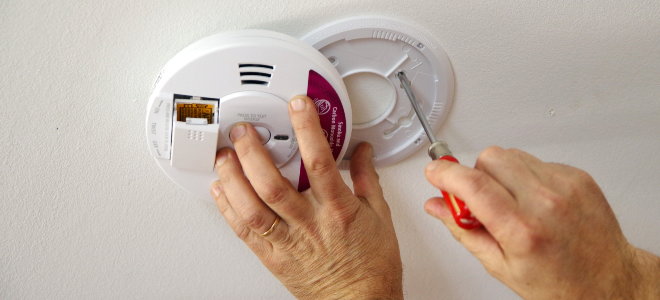 hands installing a smoke detector