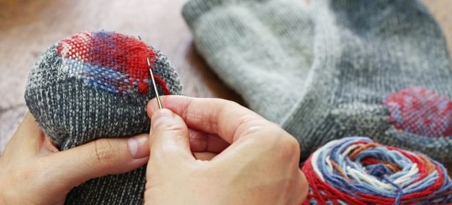 hand with needle darning the bottom of a sock
