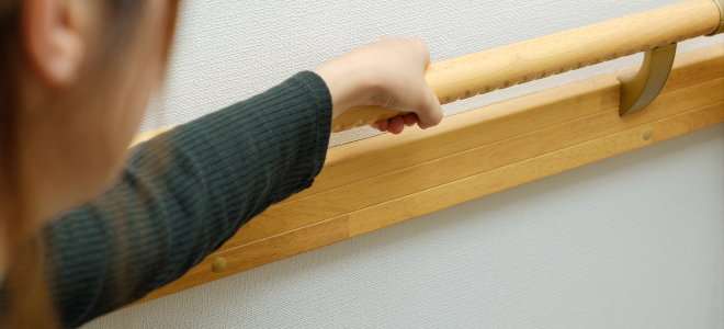 woman holding a wooden handrail in a home