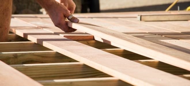 hand laying boards on a deck