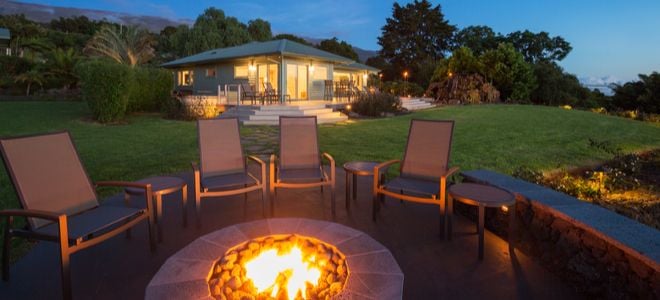 A backyard fire pit with chairs around it.