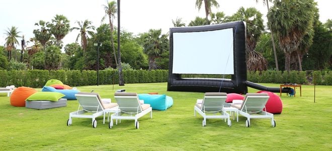 Inflatable outdoor movie screen on a lawn with lawn chairs.