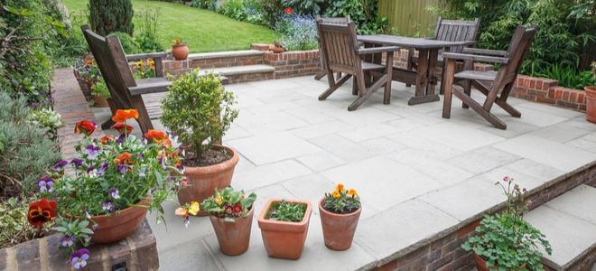 stone patio with brick walls, wood furniture, and potted plants