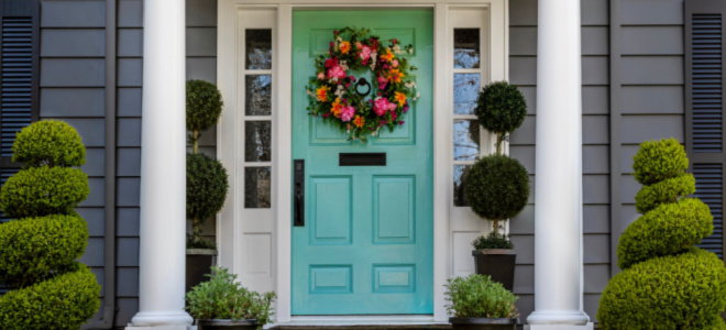 brightly painted front door with pillars and bushes