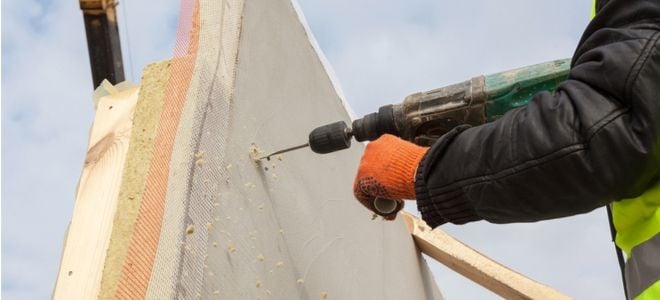 construction worker drilling through structurally insulated panel