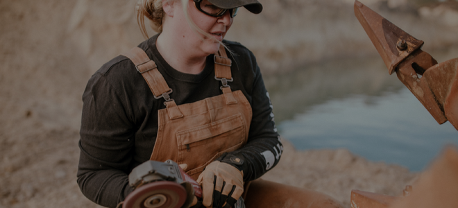 woman in overalls with power sander