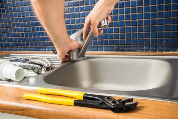 man working on a kitchen faucet