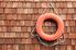 A red life ring hanging against wood siding. 