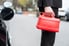 man holding a gas tank next to a car's open gas cap