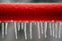 A length of red piping with icicles hanging off of it.