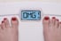 A woman standing on digital weight scale.