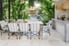 outdoor kitchen with table, chairs, plants, tile patio, and stone bar counter