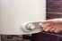A hand adjusts the knob on a wall heater.