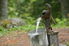 a hand pump outdoor water spout pouring water into a bucket