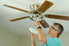 A man installing a ceiling fan. 