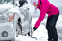 Woman shoveling snow to free her car on the road