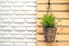 A hanging basket planter against a wood pallet and a white painted brick wall. 