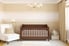 A wooden crib in a neutral baby room.