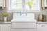 A white kitchen sink in front of a window with a beige interior.