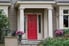 A front porch to a house with a red door.