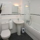 White bathroom with house plant, toilet, sink and bathtub.