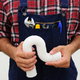 A plumber in overalls and a plaid shirt with holding a white pipe.