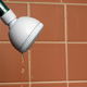Shower head dripping water with burnt sienna tiles in the background