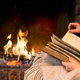 Someone reading a book by the fire. 