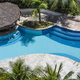 beautiful pool area with stone deck, gazebo, and palm trees from above